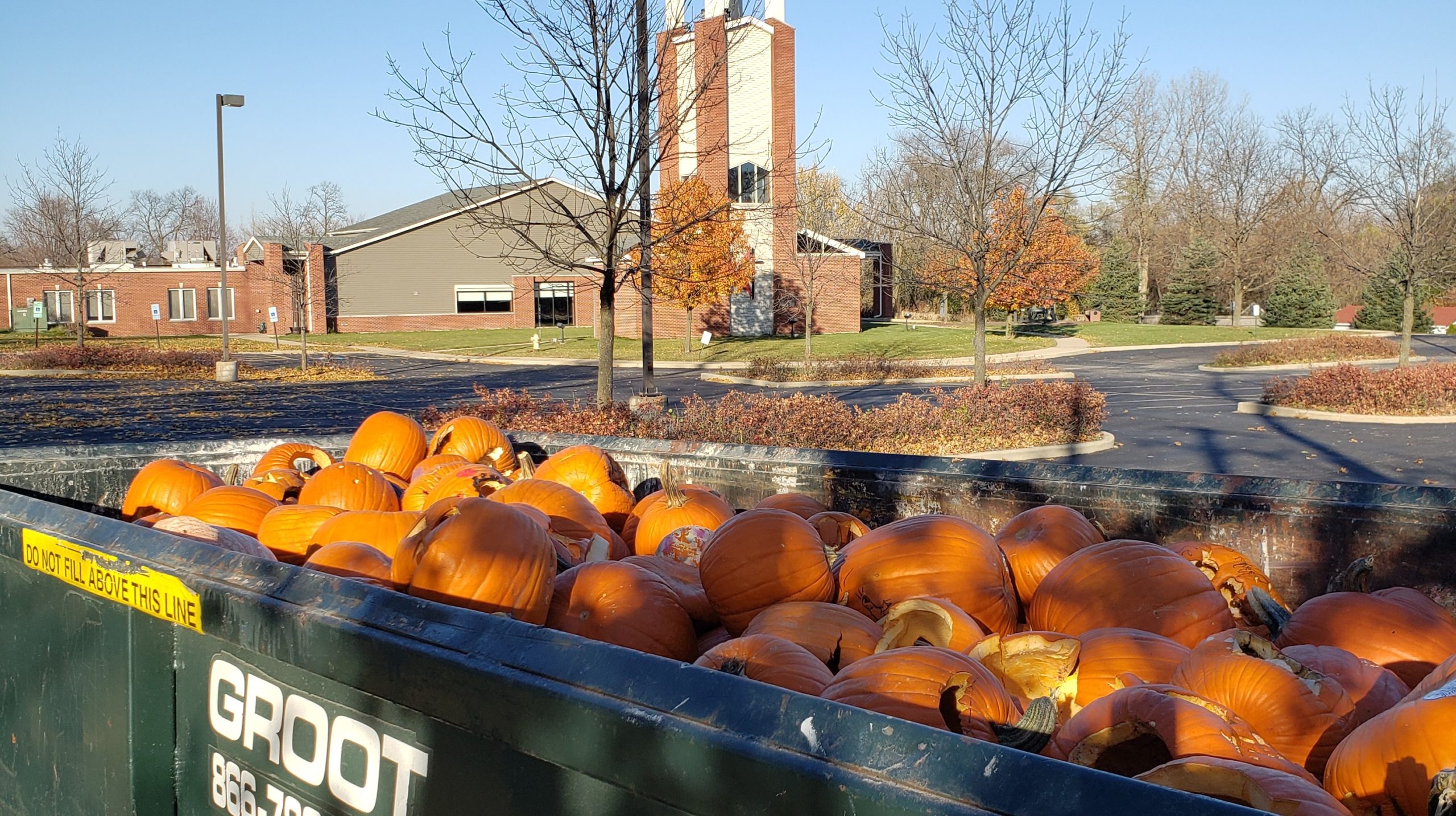 Groot dumpster filled with pumpkins in foreground with First United Methodist Church in the background